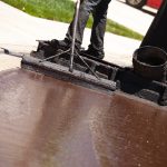 Road Worker Resurfacing Street with Hot Tar.